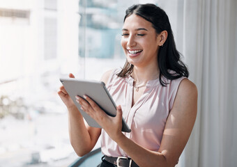 Technology eases the work load. Shot of an attractive young businesswoman standing alone in the office and using a digital tablet.