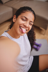 Another great sweat session down in the books. Shot of an attractive young woman sitting and taking a selfie after her workout in her living room.