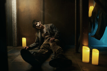 Tired and exhausted zombie sitting on floor - obrazy, fototapety, plakaty