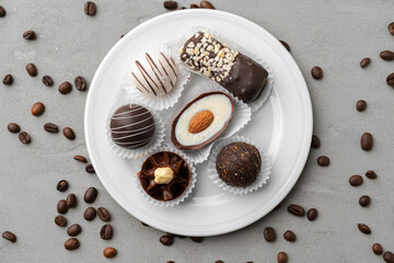 Chocolate candies in a white plate on gray background