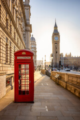 A classic, red telephone booth in front of the Big Ben clocktower in London, Westminster, during...