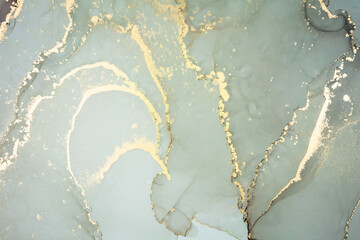 Luxury abstract fluid art painting in alcohol ink technique, mixture of gray and gold paints. Imitation of marble stone cut, glowing golden veins. Tender and dreamy design.