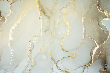 Luxury abstract fluid art painting in alcohol ink technique, mixture of pastel gray and gold paints. Imitation of marble stone cut, glowing golden veins. Tender and dreamy design.