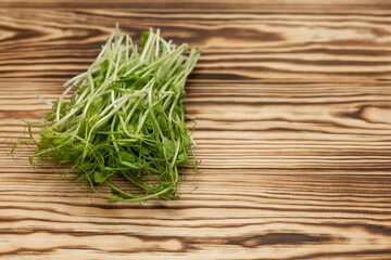 a bunch of freshly cut micro-green peas on a wooden tabletop, stylized by firing