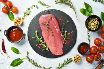 Fresh and raw fillet meat. Whole piece of beef tenderloin steaks set with spices and herbs. Meat. On a stone background.