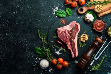 The T-bone or porterhouse steak of beef. Aged steak. Top view. On a black stone background.