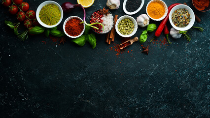 Set of Indian fragrant spices and herbs on a black stone background. Top view. Free space for text.
