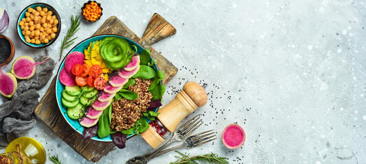 Buddha bowl: Quinoa, watermelon radish, cucumber, tomato and spinach. Delicious balanced nutrition concept on stone background.