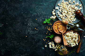 Fototapeta na wymiar Prepared popcorn in frying pan, corn seeds in bowl and corncobs on kitchen table. Top view.