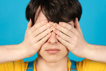 Fototapeta premium Portrait of teenager covering his eyes with hands.