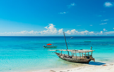 Fototapeta na wymiar Wooden fishing ship on the white sand beach on low tide, Indian ocean. Zanzibar, Tanzania