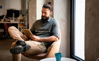 Portrait of successful handsome business man using digital tablet in office