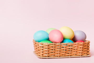 Multi colors Easter eggs in the woven basket on colored background . Pastel color Easter eggs. holiday concept with copy space