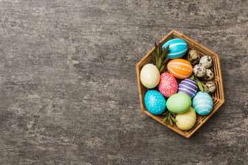 Multi colors Easter eggs in the woven basket on colored background . Pastel color Easter eggs. holiday concept with copy space