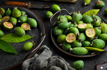 Side view of natural fresh green feijoas, on a black stone background.