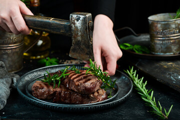 Two grilled ribeye beef steak on a plate in the hands of the chef. Food banner. On a black background.