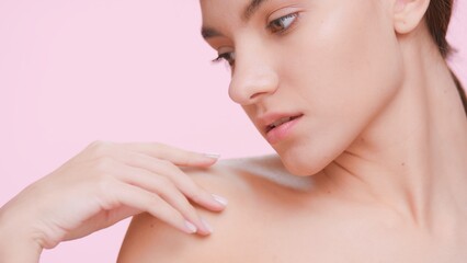 Obraz na płótnie Canvas Beauty portrait of young woman, who softly strokes her skin from a clavicle to the shoulder | skin care product commercial concept.