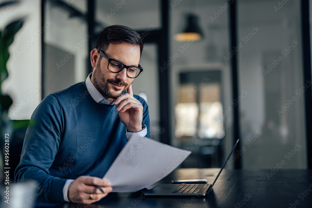 Wall mural focused ambitious man, holding a paper, creating a document.