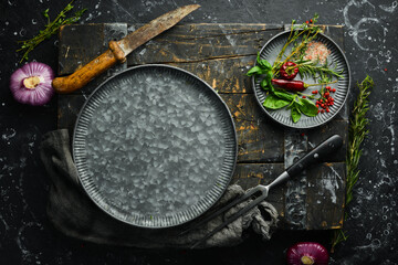Dark kitchen table with spices and kitchen utensils. On a black stone background.
