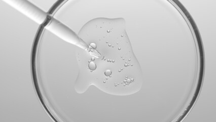 Grayscale macro shot of gel with different sized tiny bubbles comes out from chemical dropper into...