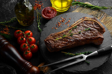 Grilled New York beef steak on the bone, herbs and spices. Juicy cooked steak. Top view. Rustic...
