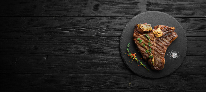 Aged Beef T-Bone steak. Juicy cooked steak with rosemary and spices. Top view. Rustic style. Flat Lay.