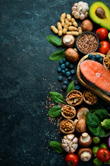 Obraz na płótnie Canvas Heart health foods: salmon, avocados, blueberries, broccoli, nuts and mushrooms. On a black stone background. Top view. Copy space.
