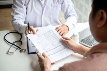 Male doctor holding health check documents and explaining the results of the examination to the...