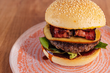 Close up of a juicy burger, with meat, salad, bacon, and cheese.