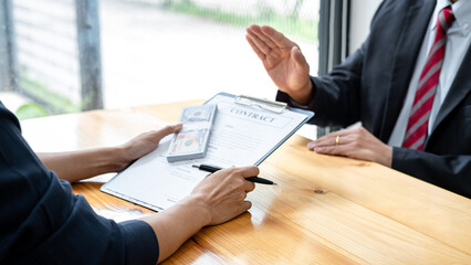 Businessman is refuses to accept banknote money and terms of contract from bribe employer in signing contract