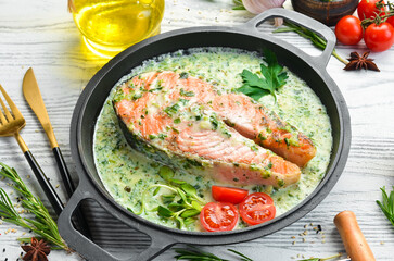 Salmon steak with creamy spinach sauce in a pan. Restaurant food. Seafood. Rustic style. Flat Lay.