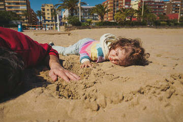Little girl playing on the sand with her dad