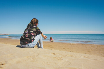 Young single mom caring her little girl at the beach