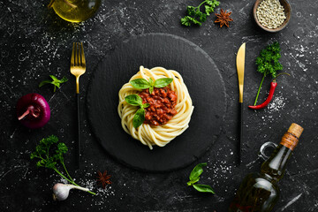 Fototapeta na wymiar Spaghetti pasta with bolognese sauce and basil in a black stone plate. Italian food. Top view. Free space for text.