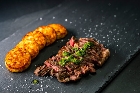 beef steak with potato patties on a dark background