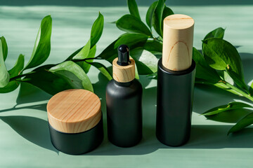 Cosmetic container mock-ups. Trendy Background for branding and packaging presentation. Natural skincare beauty product concept. Serum. essence and spray beauty set with green leaves and hard shadows