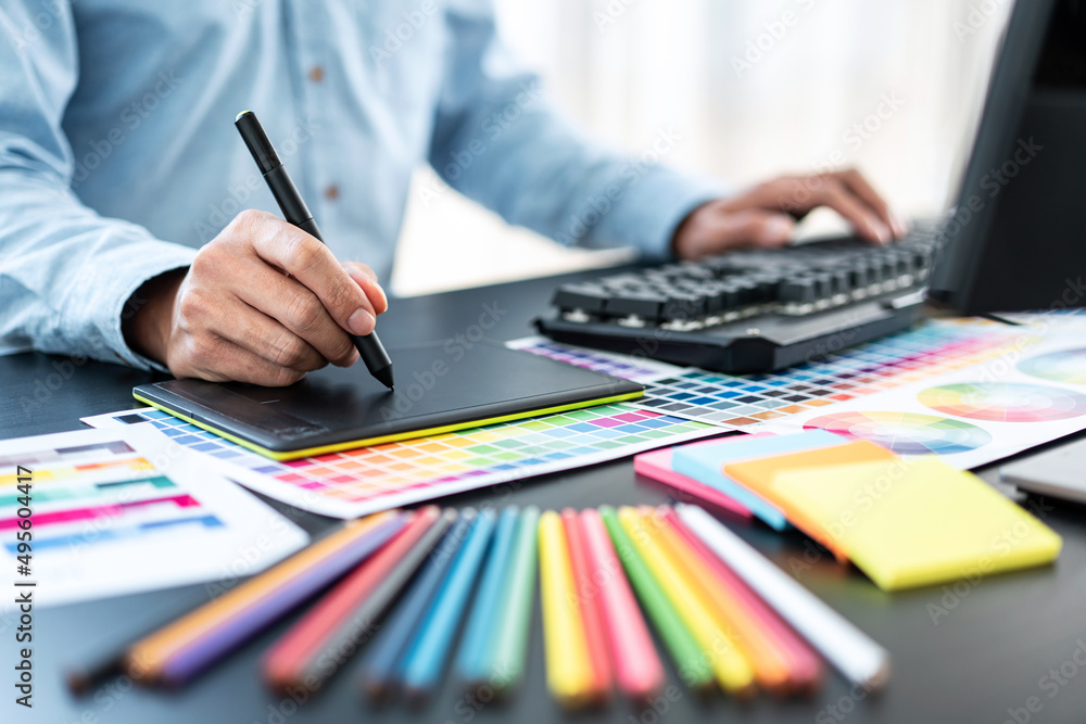 Fototapete Young creative graphic designer working on color selection and drawing on graphics tablet at workplace, Color swatch samples chart for selection coloring