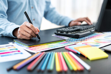 Young creative graphic designer working on color selection and drawing on graphics tablet at workplace, Color swatch samples chart for selection coloring