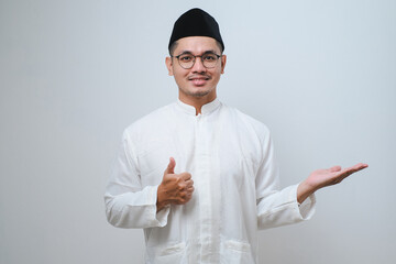 Asian muslim man wearing koko clothes showing palm hand and doing ok gesture with thumbs up