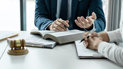 Male lawyer is pointing on legal document to explaining about consultation terms and condition to businesswoman before signing on contract at law firm