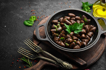 Fried chicken hearts with parsley and spices in a metal pan. Top view. Free space for text.