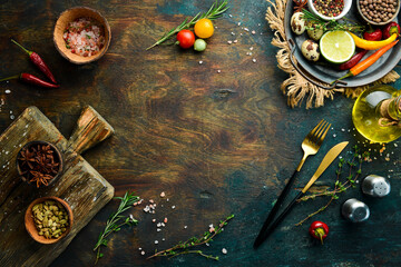 Cutlery on a black stone table with vegetables and spices. Food background. Top view. Rustic style.
