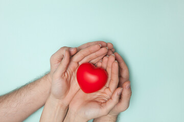 Man and woman hands holding red heart, health care, donate and family insurance concept, world heart day.