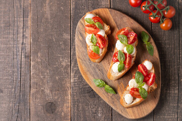 Italian tomato and cheese bruschetta. Tapas, antipasti with chopped vegetables, herbs and oil on grilled ciabatta and baguette bread.