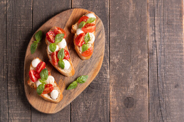 Italian tomato and cheese bruschetta. Tapas, antipasti with chopped vegetables, herbs and oil on grilled ciabatta and baguette bread.