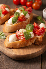 Italian tomato and cheese bruschetta. Tapas, antipasti with chopped vegetables, herbs and oil on grilled ciabatta and baguette bread.