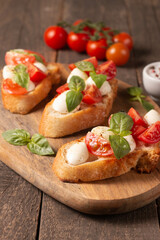 Italian tomato and cheese bruschetta. Tapas, antipasti with chopped vegetables, herbs and oil on grilled ciabatta and baguette bread.