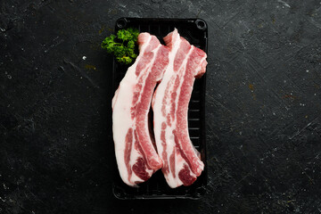 Pork. Raw fresh pork ribs on black slate stone background. Top view. Cooking. © Yaruniv-Studio