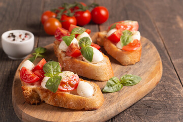 Italian tomato and cheese bruschetta. Tapas, antipasti with chopped vegetables, herbs and oil on grilled ciabatta and baguette bread.