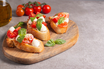 Italian tomato and cheese bruschetta. Tapas, antipasti with chopped vegetables, herbs and oil on grilled ciabatta and baguette bread.